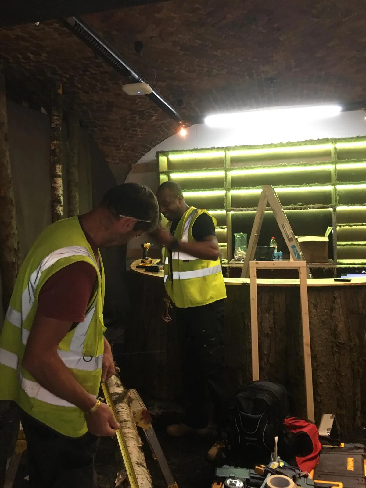 workers building green-lit curved bar