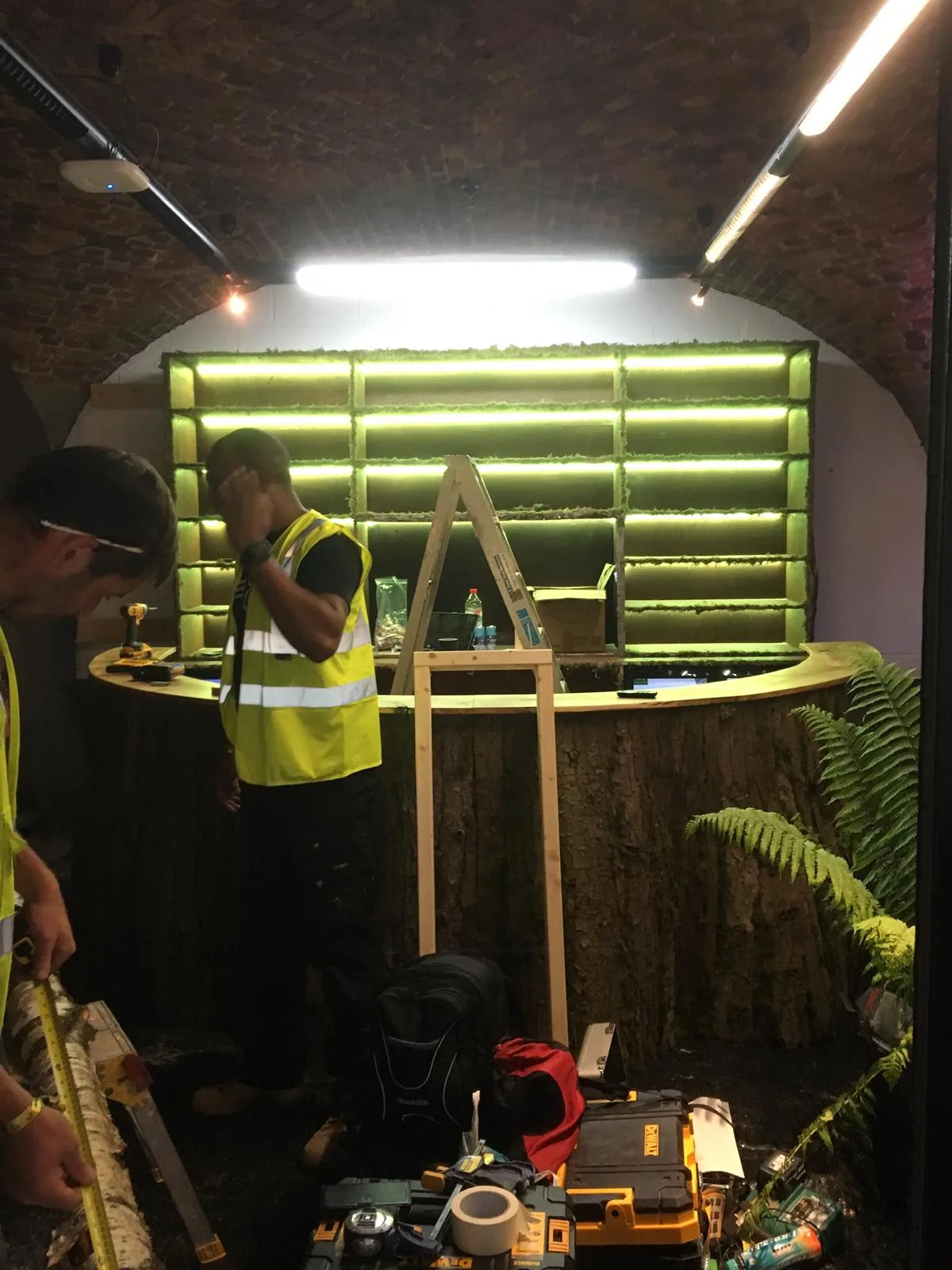 worker at green-lit curved bar